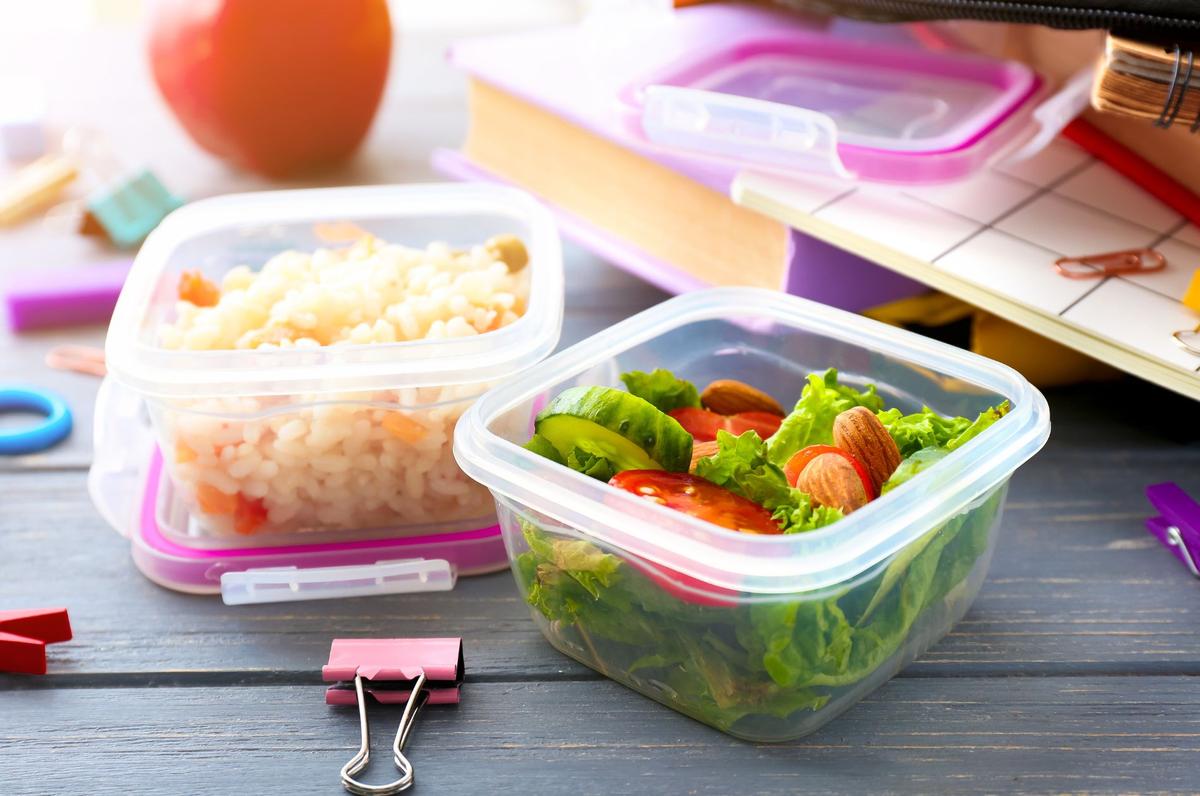 Plastic tupper ware with healthy food on wooden table with stationary