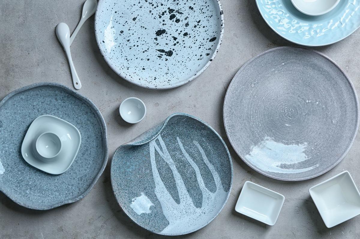 Blue and grey colored glazed ceramic plates and tableware on grey tabletop