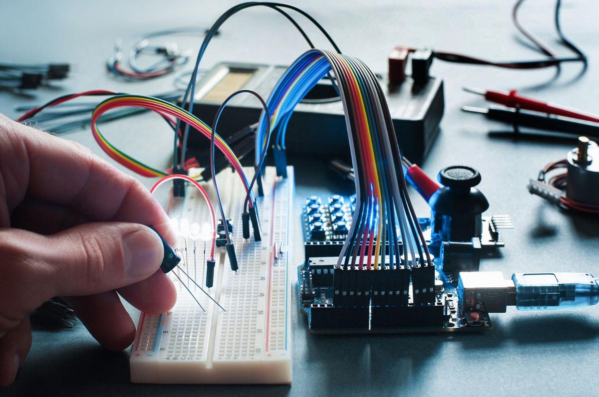 A person holding a multicolored wires and computer components