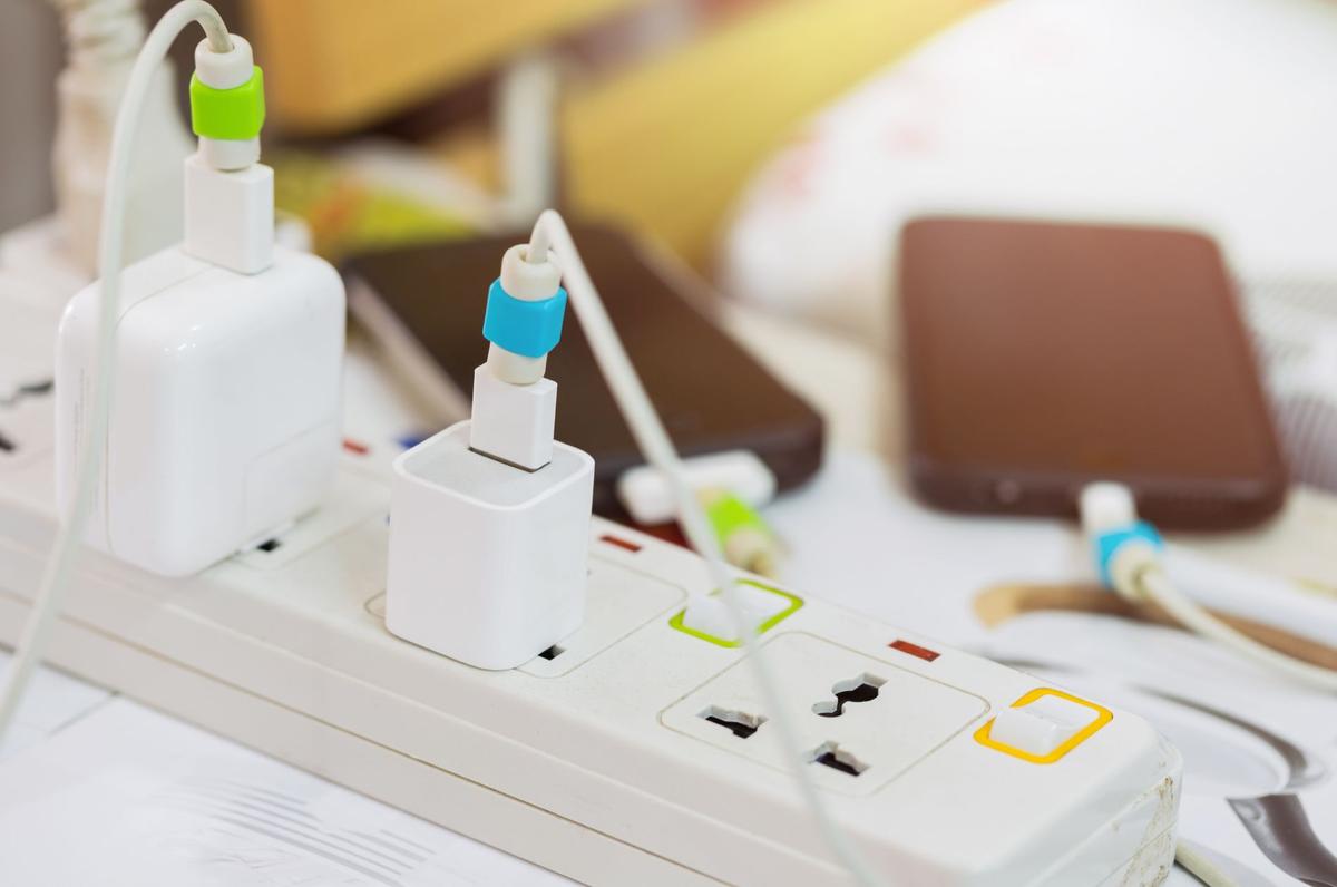 A white power strip with multiple electronic devices plugged in